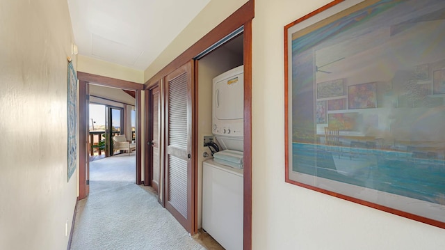 hall with light colored carpet and stacked washer and clothes dryer