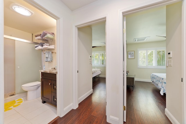 hallway featuring visible vents, baseboards, and dark wood-type flooring