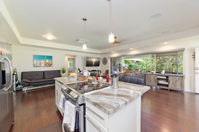 kitchen featuring a center island, decorative light fixtures, stainless steel appliances, open floor plan, and white cabinetry