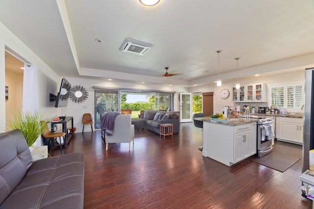 kitchen featuring light stone counters, white cabinetry, open floor plan, hanging light fixtures, and stainless steel range with electric stovetop