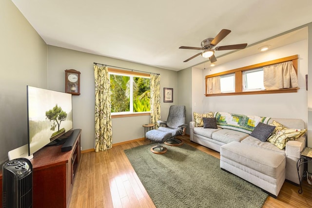 living room with light wood finished floors, baseboards, and a ceiling fan