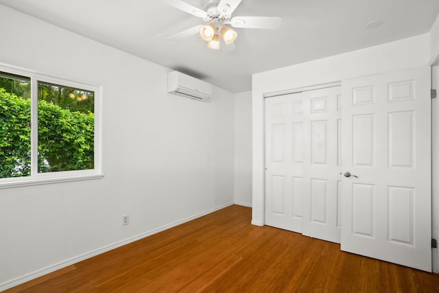 6450 Olohena Rd, Kapaa, HI 96746 - unfurnished bedroom with a wall unit AC, wood finished floors, a closet, baseboards, and a ceiling fan