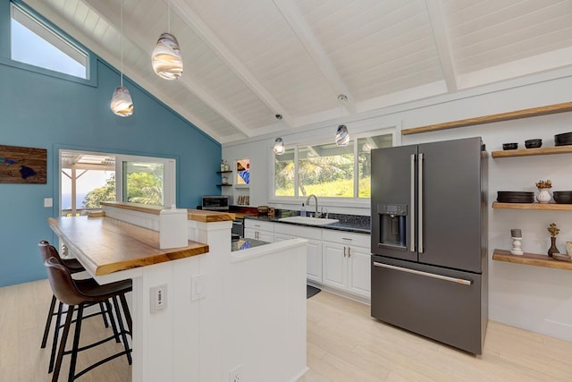 kitchen with high quality fridge, hanging light fixtures, white cabinetry, open shelves, and a sink