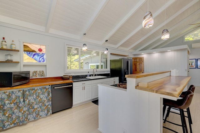 kitchen featuring butcher block countertops, hanging light fixtures, black fridge, dishwasher, and stainless steel microwave