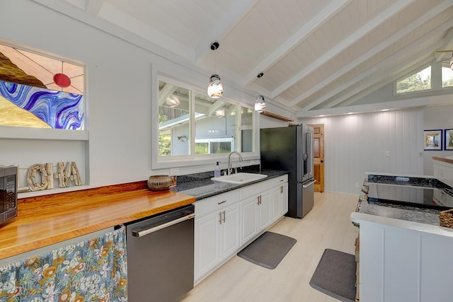 kitchen featuring vaulted ceiling with beams, appliances with stainless steel finishes, glass insert cabinets, white cabinets, and a sink