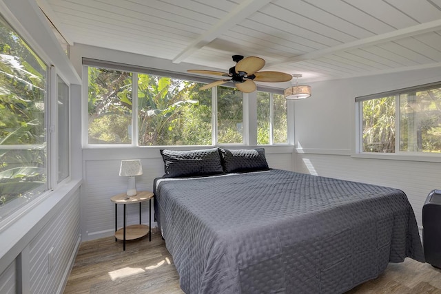 bedroom featuring multiple windows, beamed ceiling, and wood finished floors