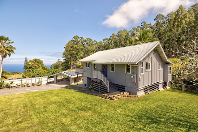 view of front facade featuring metal roof, stairway, board and batten siding, and a front yard