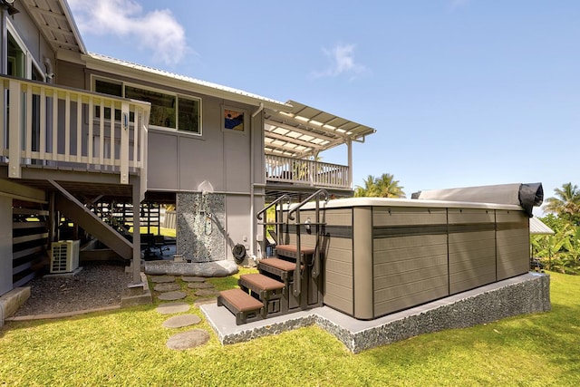 exterior space featuring metal roof, a yard, stairway, and a hot tub