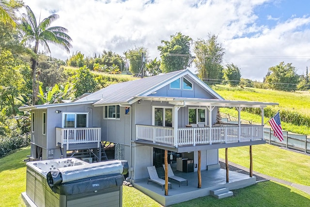 rear view of property with metal roof, a yard, and a wooden deck