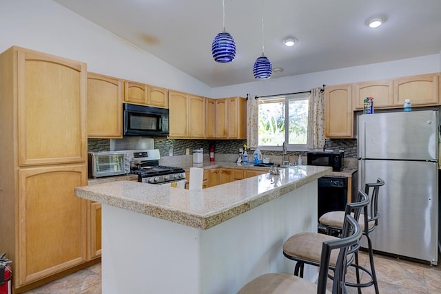 kitchen featuring lofted ceiling, light brown cabinetry, appliances with stainless steel finishes, and a breakfast bar area