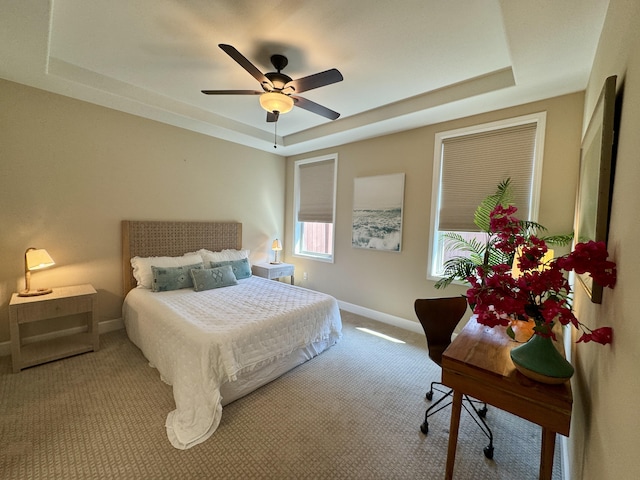 bedroom featuring a tray ceiling, a ceiling fan, baseboards, and carpet floors