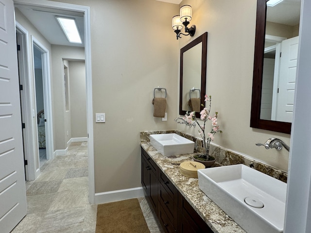 full bathroom featuring double vanity, baseboards, and a sink