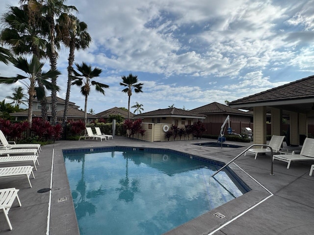 community pool featuring a patio, fence, and an outbuilding