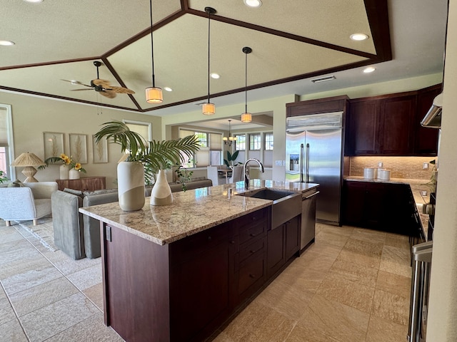 kitchen with a center island with sink, a sink, stainless steel appliances, vaulted ceiling, and open floor plan