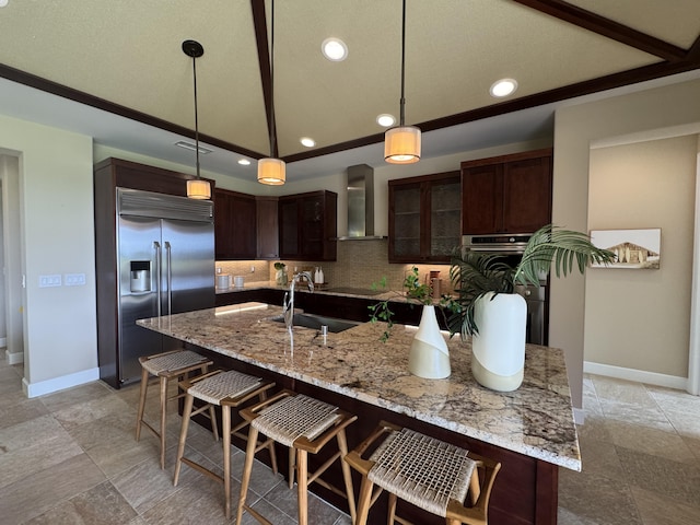 kitchen featuring a breakfast bar area, dark brown cabinetry, appliances with stainless steel finishes, wall chimney exhaust hood, and tasteful backsplash