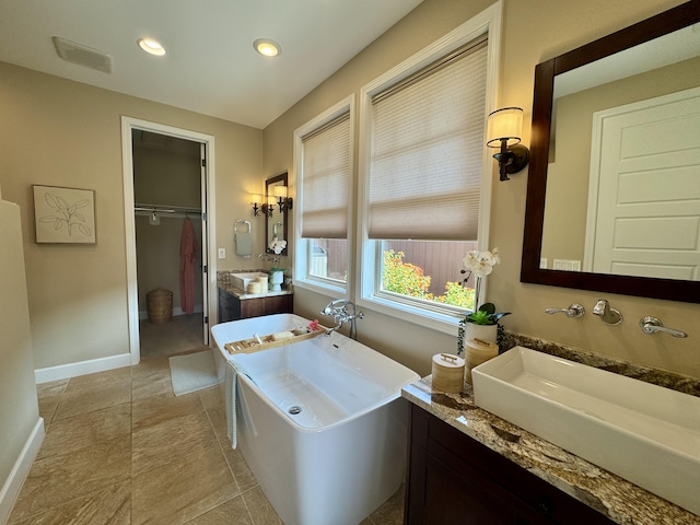 bathroom with baseboards, a freestanding bath, two vanities, recessed lighting, and a sink