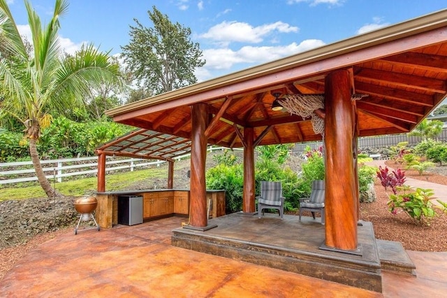 view of patio featuring fence, an outdoor kitchen, and a gazebo