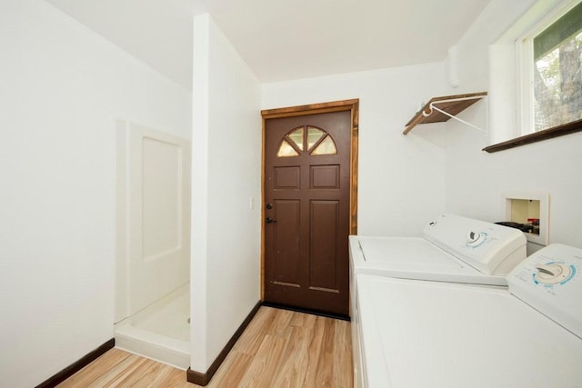 clothes washing area featuring baseboards, washing machine and clothes dryer, and light wood-style floors