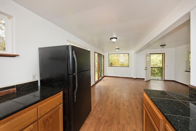 kitchen featuring baseboards, tile counters, freestanding refrigerator, brown cabinetry, and dark wood finished floors