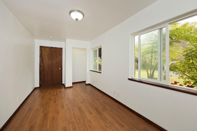 empty room with a wealth of natural light, baseboards, and wood finished floors