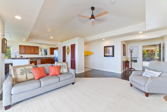 living area with a ceiling fan, recessed lighting, a raised ceiling, and baseboards