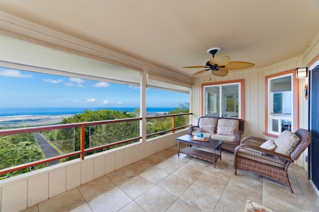 sunroom featuring a water view and a ceiling fan