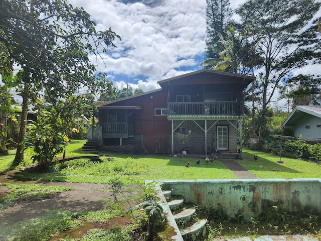 back of property with a balcony, a sunroom, and a yard