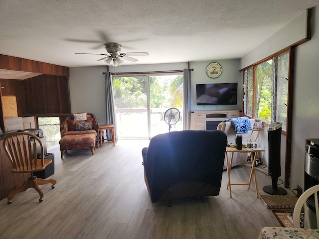 living room with a ceiling fan, a healthy amount of sunlight, a textured ceiling, and wood finished floors