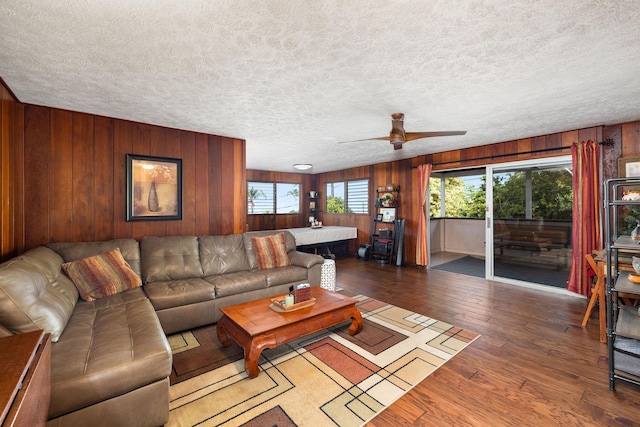 living room featuring plenty of natural light, wooden walls, a textured ceiling, and wood finished floors