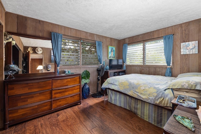 bedroom featuring a textured ceiling, wood walls, and wood finished floors