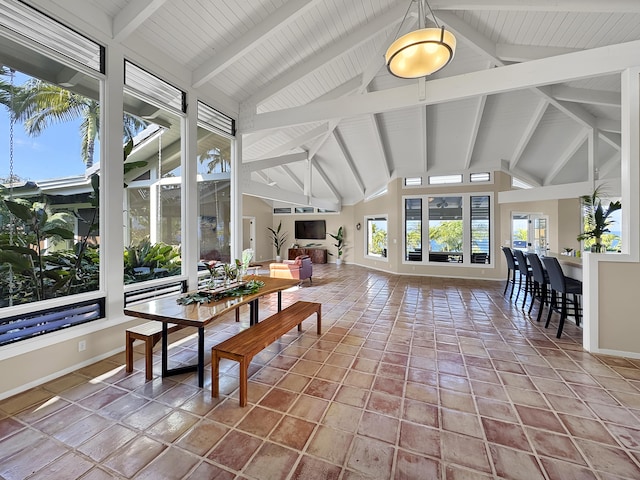 sunroom / solarium featuring vaulted ceiling with beams