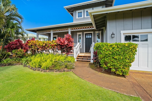 entrance to property with a yard, a porch, and board and batten siding