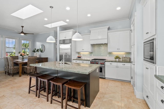 kitchen featuring a sink, backsplash, a kitchen breakfast bar, and built in appliances