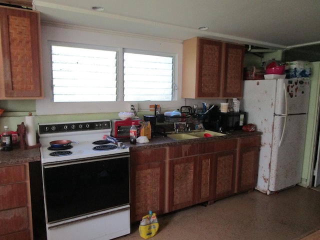 kitchen featuring white appliances, brown cabinetry, dark countertops, and a sink