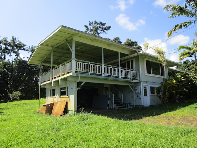 back of property featuring a lawn, a deck, and stairs