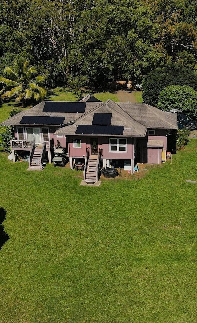 exterior space featuring stairs, solar panels, and a lawn