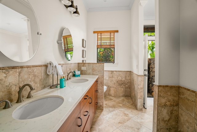 bathroom featuring toilet, crown molding, tile walls, and a sink