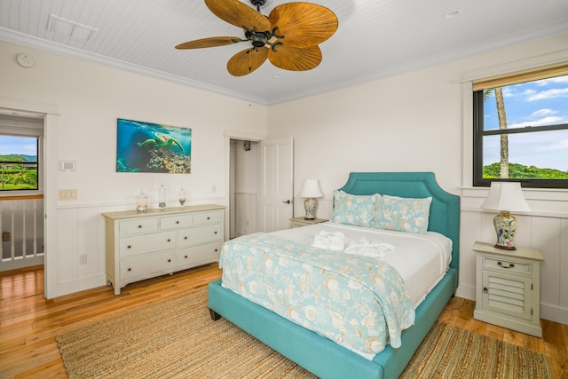 bedroom featuring light wood-style floors, visible vents, ornamental molding, and a ceiling fan