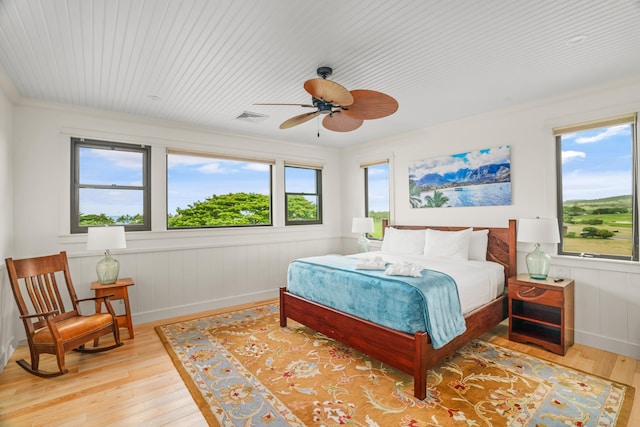 bedroom with a ceiling fan, a wainscoted wall, visible vents, and hardwood / wood-style flooring