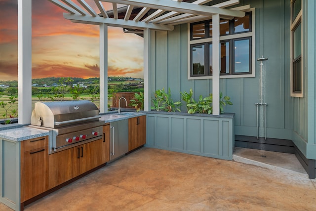 patio terrace at dusk with an outdoor kitchen, area for grilling, and a sink