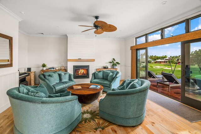 living room with ceiling fan, a fireplace, visible vents, ornamental molding, and light wood-type flooring