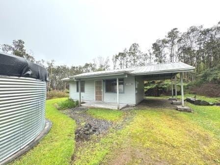 back of property featuring an attached carport, metal roof, and a yard