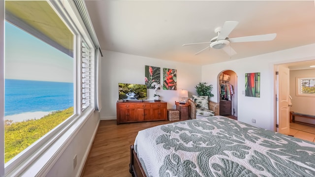 bedroom with a ceiling fan, arched walkways, baseboards, and wood finished floors