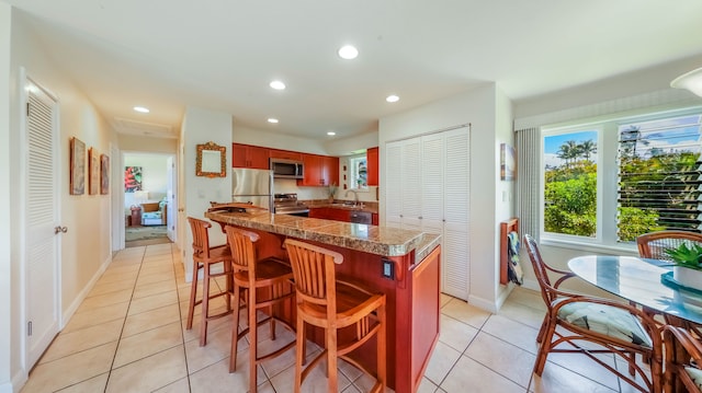 kitchen featuring light tile patterned floors, appliances with stainless steel finishes, a breakfast bar, and recessed lighting