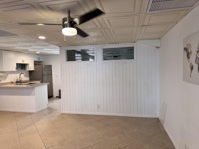 interior space with light tile patterned floors, a ceiling fan, baseboards, and an ornate ceiling