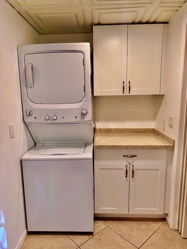 laundry room with stacked washer / dryer, light tile patterned flooring, and cabinet space