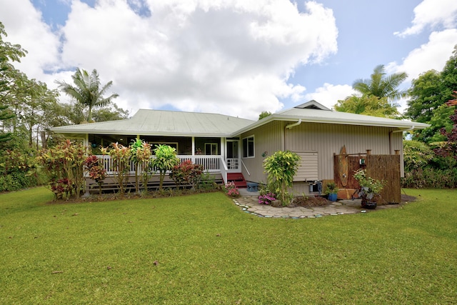 rear view of property featuring covered porch and a lawn