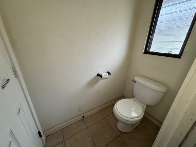 bathroom featuring tile patterned flooring, baseboards, and toilet