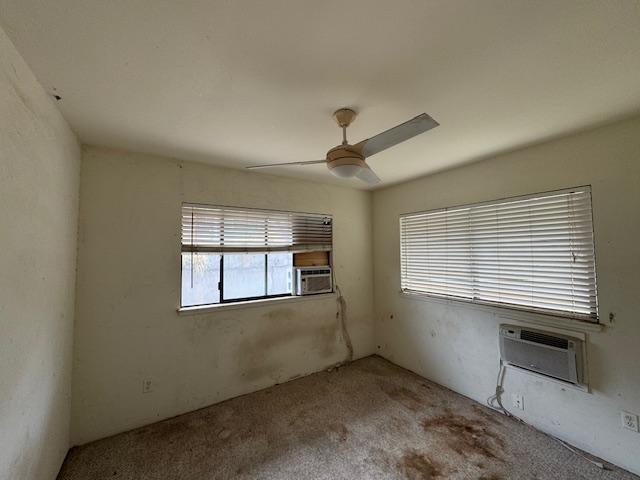 unfurnished room with light carpet, ceiling fan, cooling unit, and a wall mounted AC