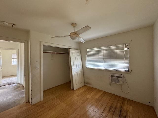 unfurnished bedroom with light wood finished floors, a closet, a wall mounted AC, and a ceiling fan